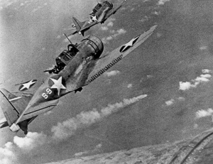 Two American SBD's fly over a Japanese ship, presumably Mikuma, during the Battle of Midway.